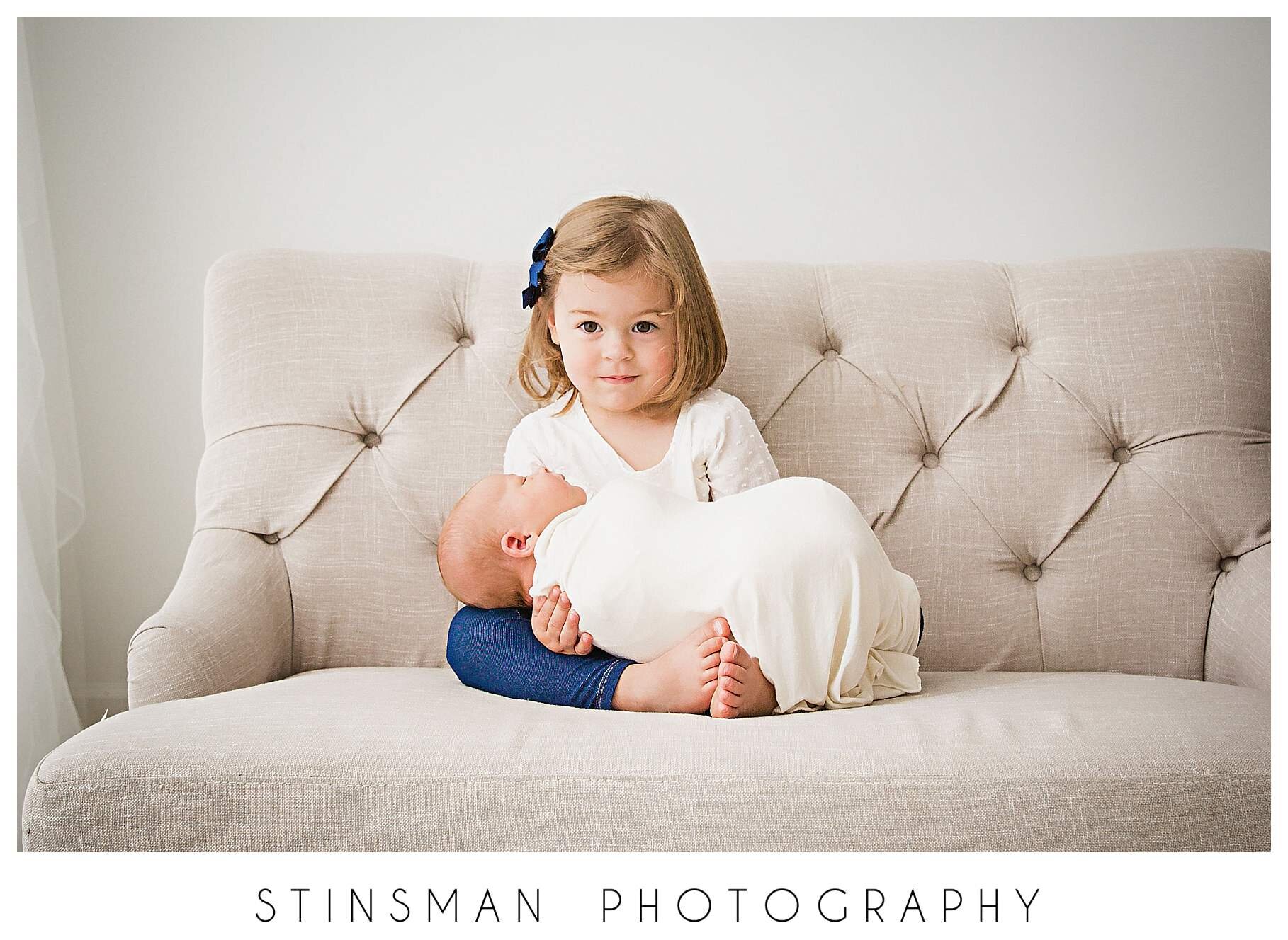 2-year-old-girl-holding-baby-brother-for-newborn-pics.jpeg
