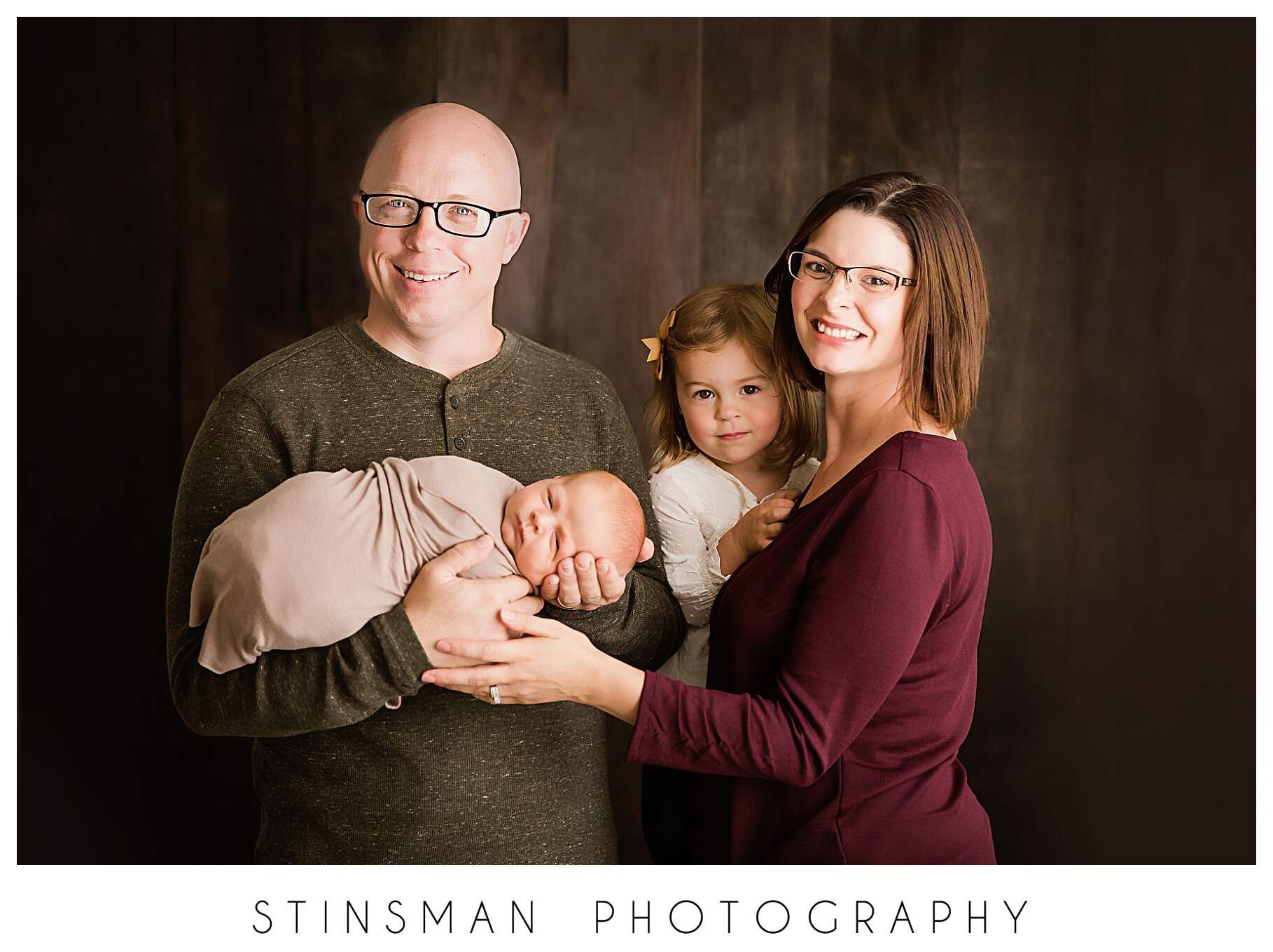 family-photo-on-brown-wood-backdrop-at newborn-session.jpeg