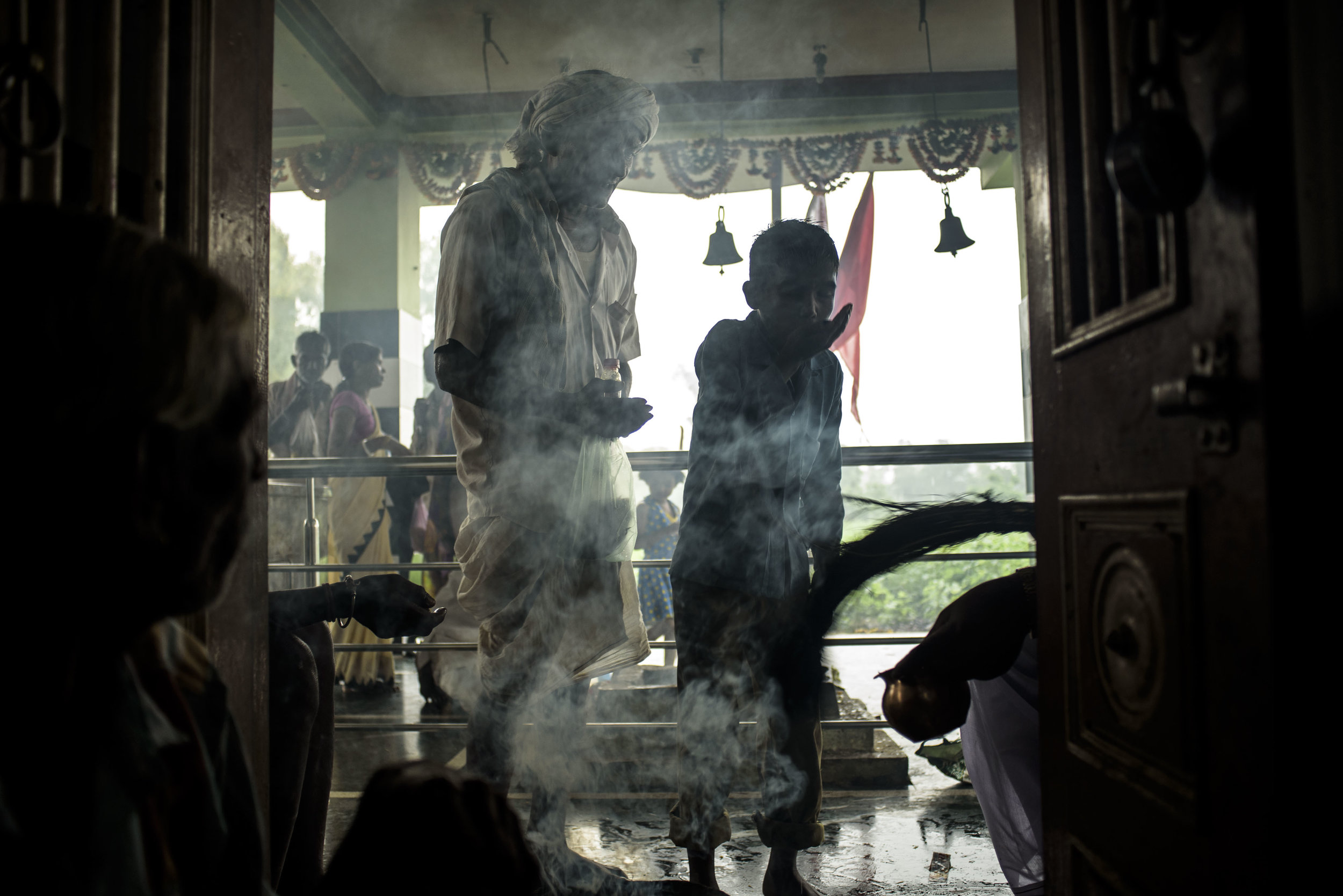 Smoke from burning a bundle of incense sticks fills up spaces within the temple, while people await their turn to meet the head Bhopa. 