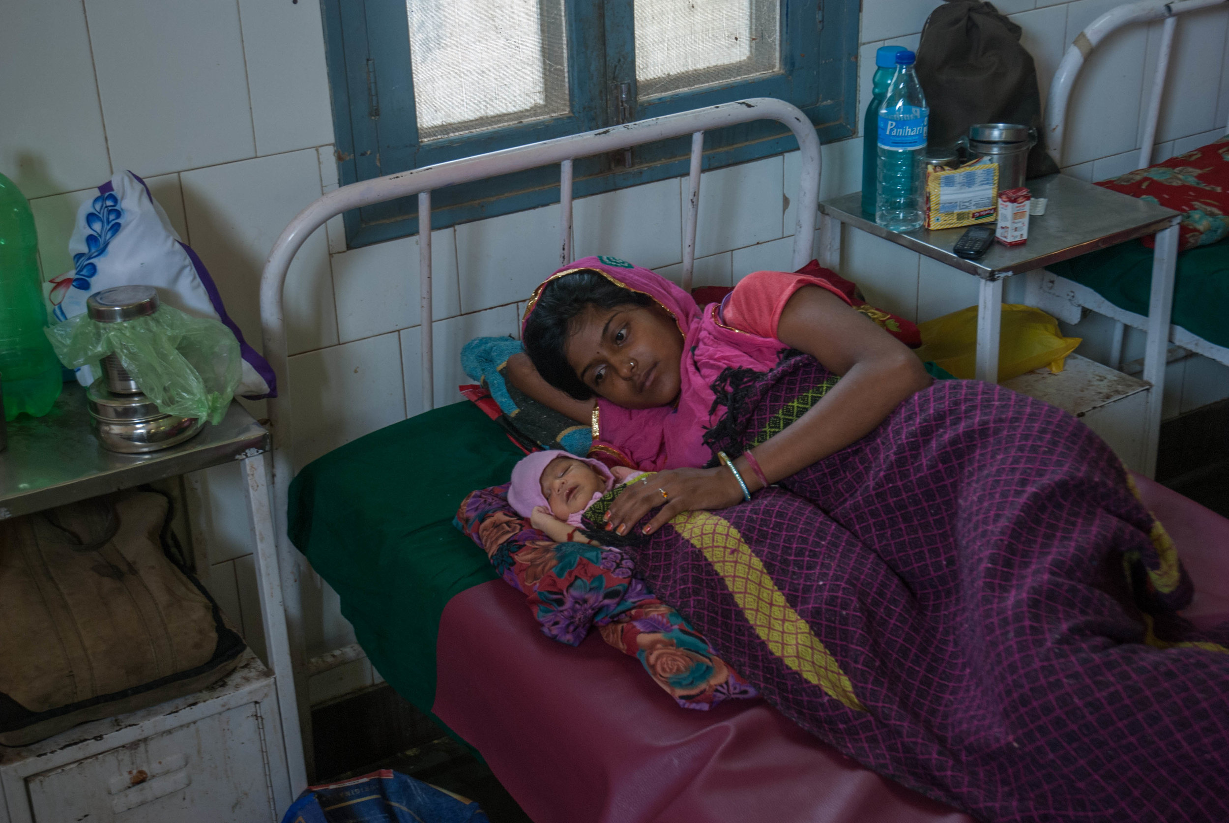  In the maternity ward, a 19-year old mother lies in bed with her daughter. 