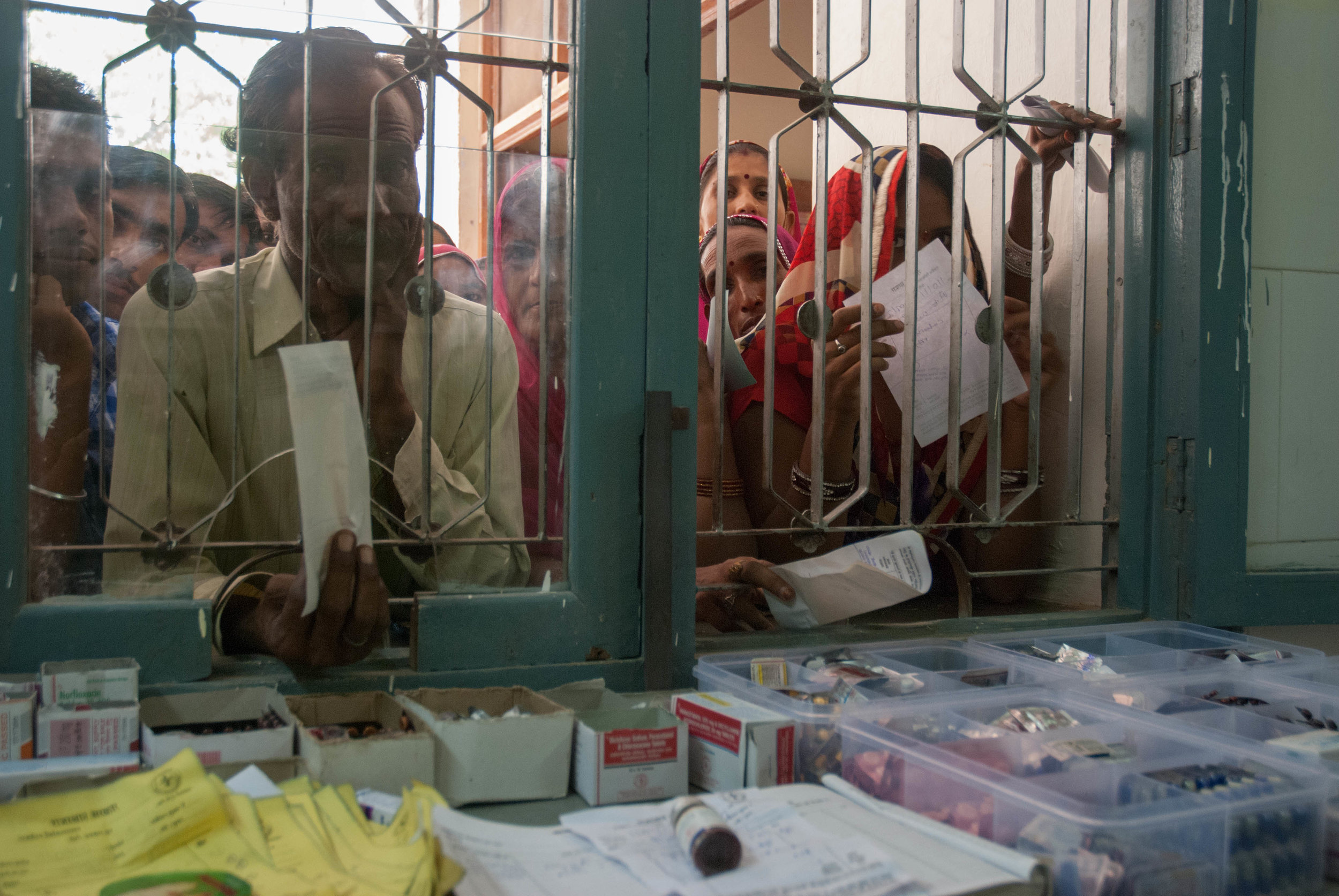 Patients crowd around a single drug-distribution window with their prescriptions to collect their free medications at the Community Health Center (CHC), Nokah.
