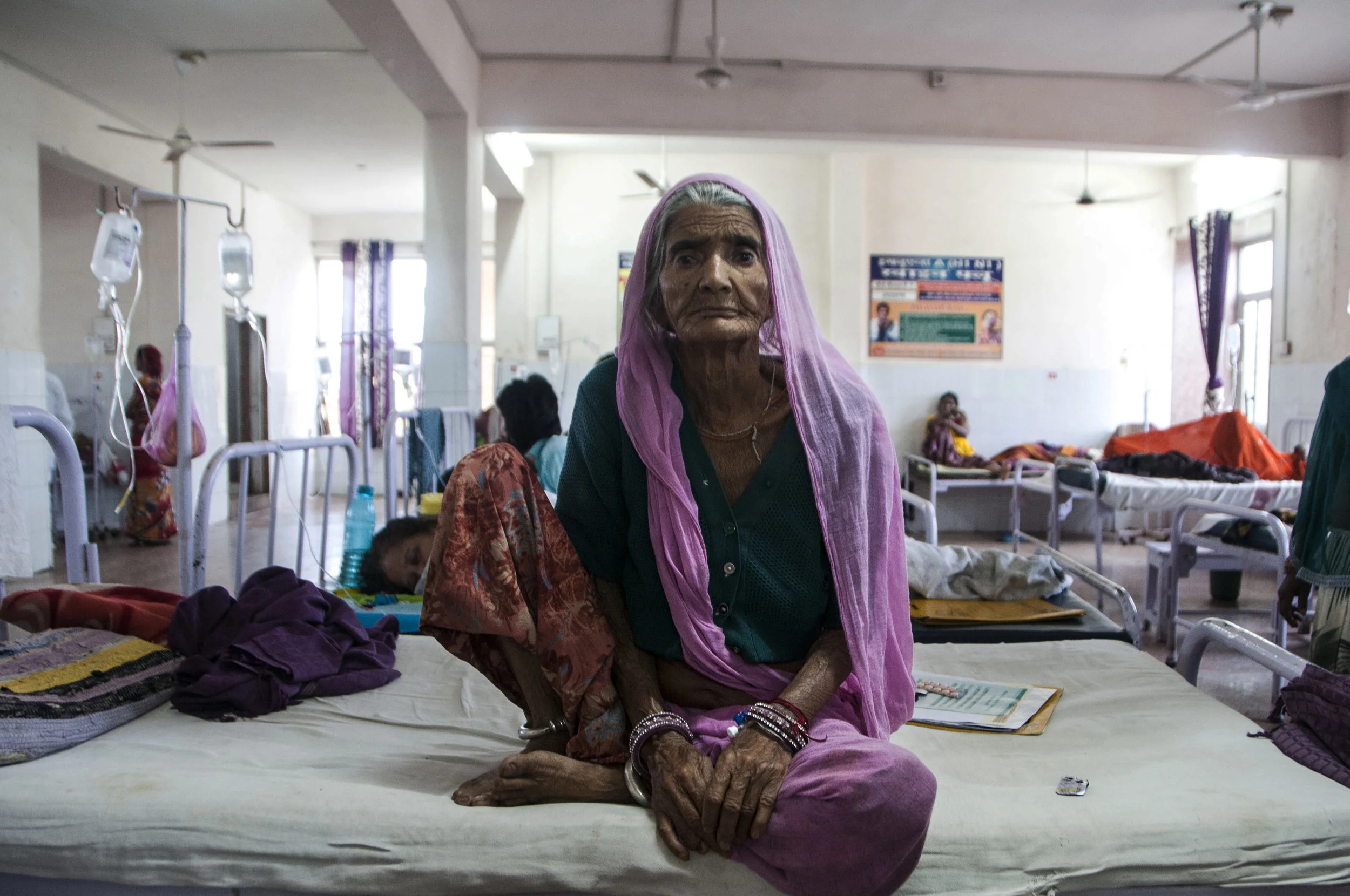 Mangi says that she’s probably older than 70 and complains of pain in her lower abdominal area. Her sonogram report says she is 60, and has gross ascitis. She’s been coming to Chittorgarh District Hospital for around three years to seek treatment and the scheme covers all her medication. She says that the scheme has been the most helpful for chronic patients.