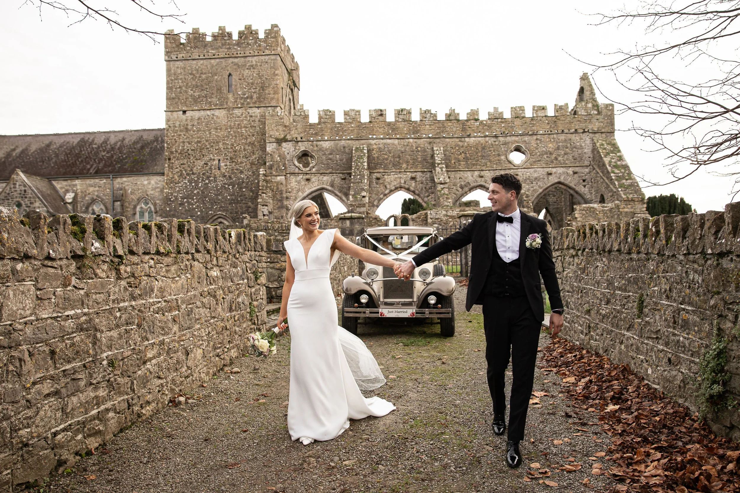 gowran-abbey-bride-and-groom-walking-and-smiling-folkster-gowns-kate-tobin-liam-ryan-wexford-senior-hurler-donal-o'connor-oc-wedding-videography-daragh-mccann-stargaze-photography.jpg