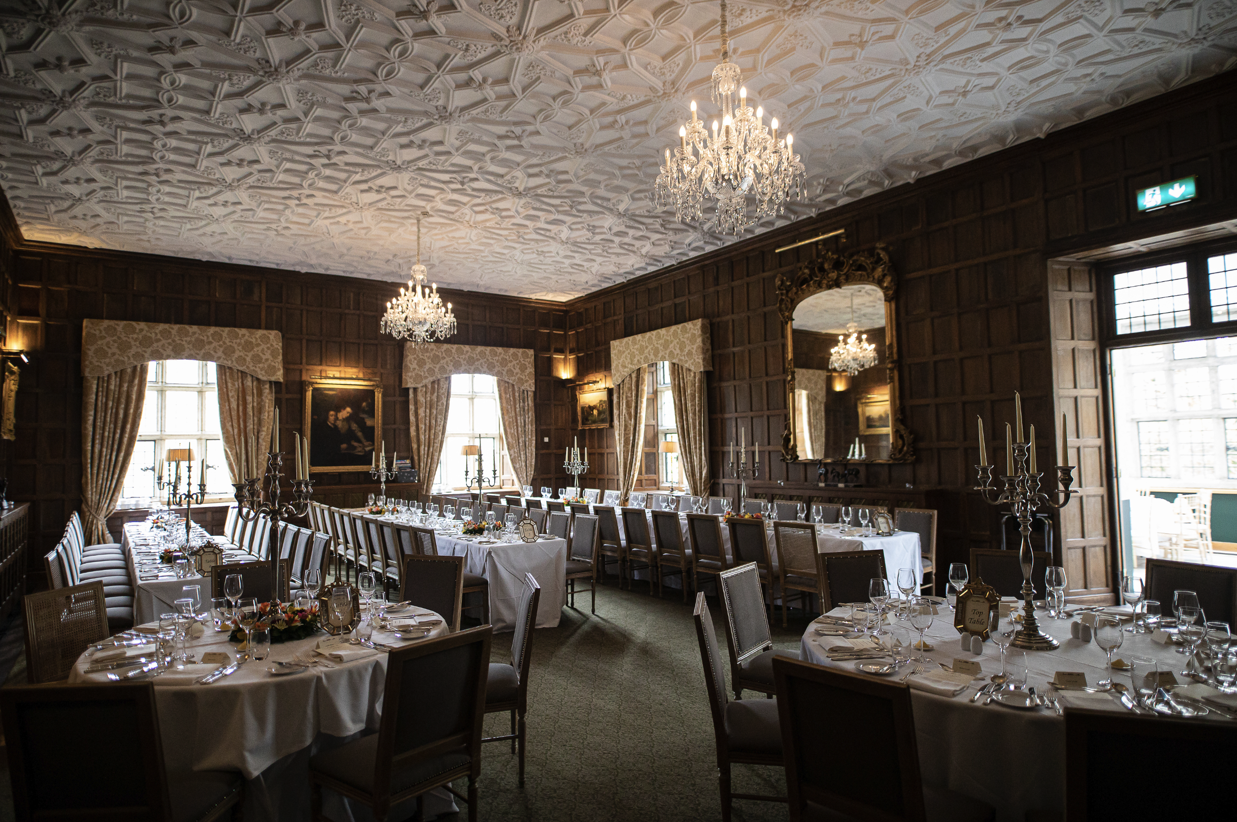 Elegant dining room with chandeliers, long tables, and place settings.