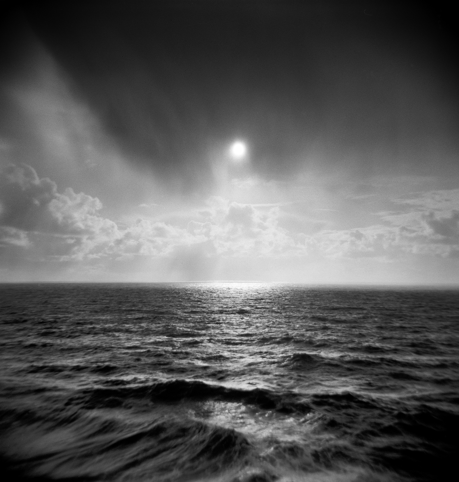 Sun through clouds over ocean holga.jpg