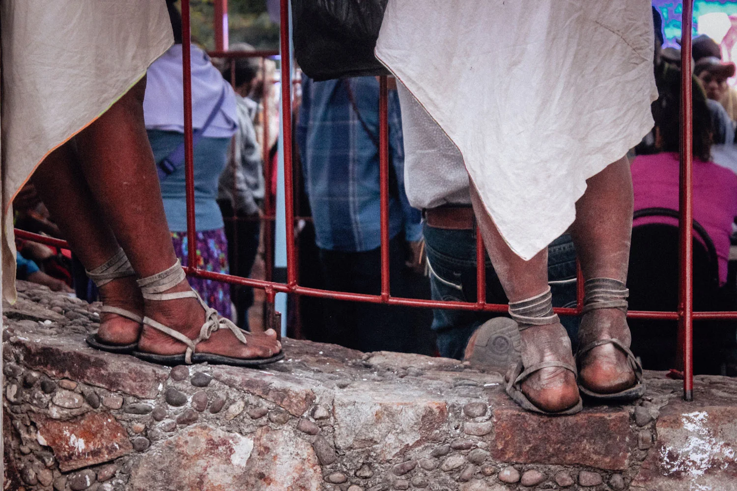 Two men in worn huaraches made with tire tread and leather straps.