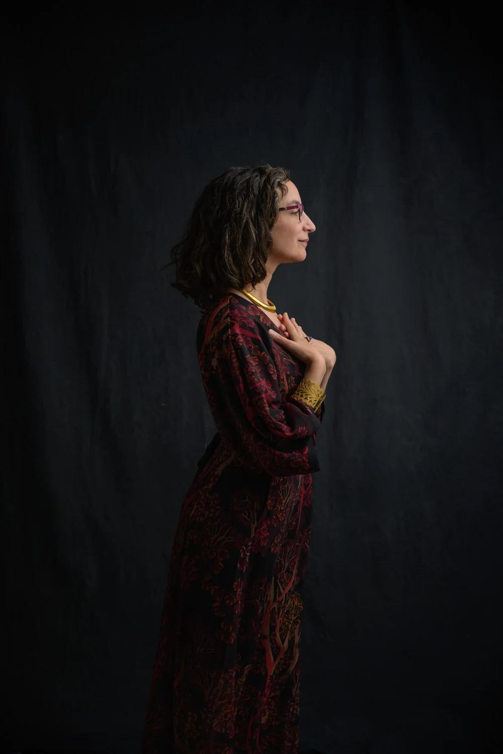 Young woman in her 30s. Profile image with her hands crossed on her chest.