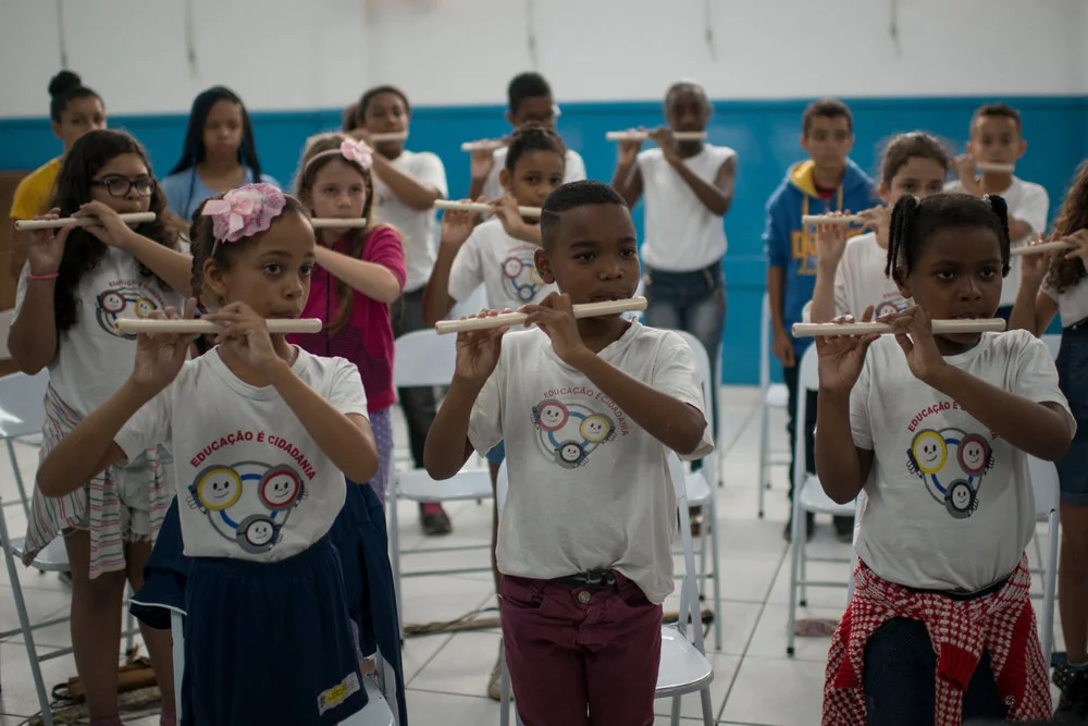 Dez. 6, 2017. Alunos olham atentamente para a maestrina em ensaio com a flauta pífaro. Por conta da sua posição enquanto mulher, negra, de criação simples que hoje ocupa um cargo estritamente masculino, Sarah se tornou um espelho para as crianças da periferia, que agora têm para onde olhar além da siderúrgica.