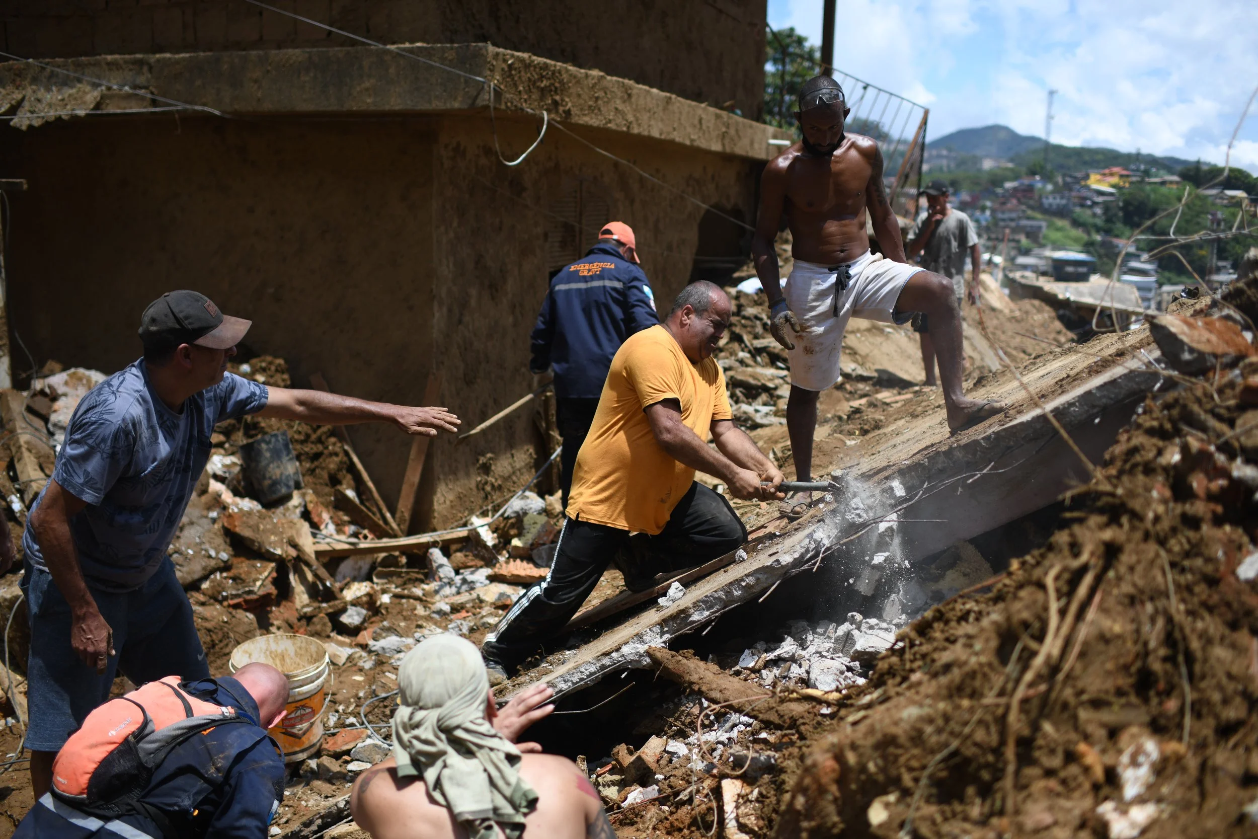  Flávio Menezes, de amarelo, quebra uma laje com a ajuda de moradores e voluntários para tentar resgatar seus parentes que foram soterrados. No total, Flávio perdeu 10 familiares no Morro da Oficina. 17 Fev, 2022. 