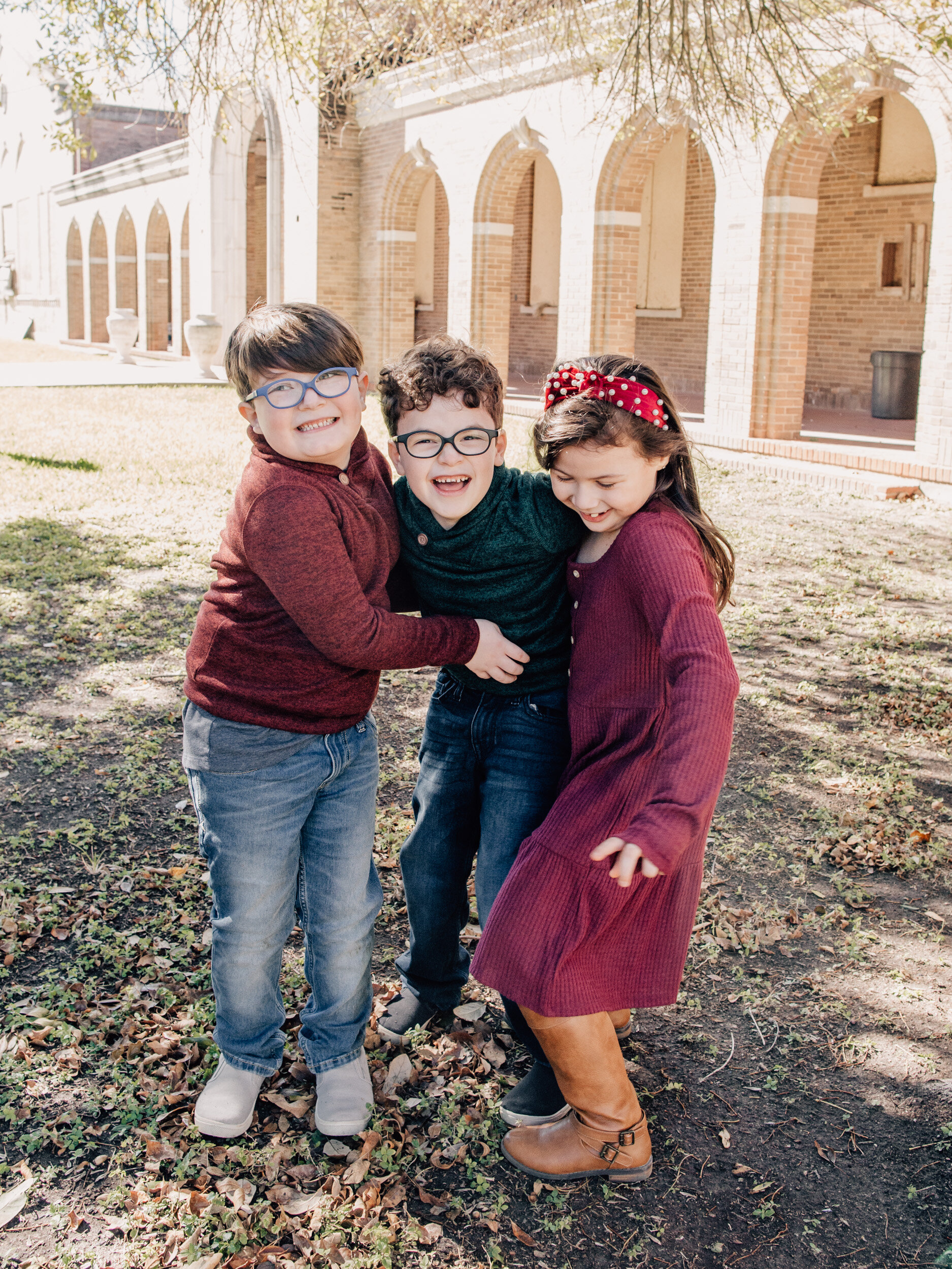 two-boys-one-girl-giggle-in-front-of-arched-brick-building-in-edinburg-texas1.jpg
