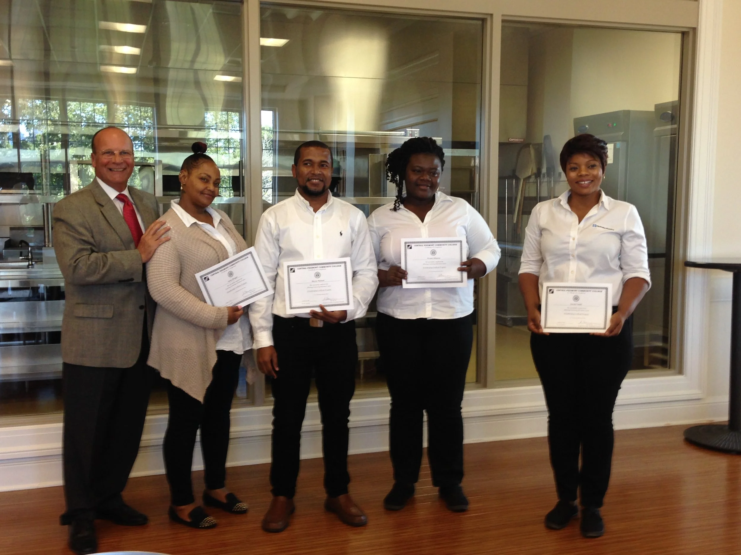 Vince Chelena, CAHA Executive Director, with recent graduates from the CPCC housekeeping training program.