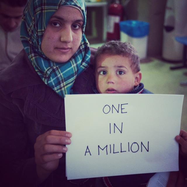  Bushra with her son, holding a sign saying “One in a Million” (UNHCR) 