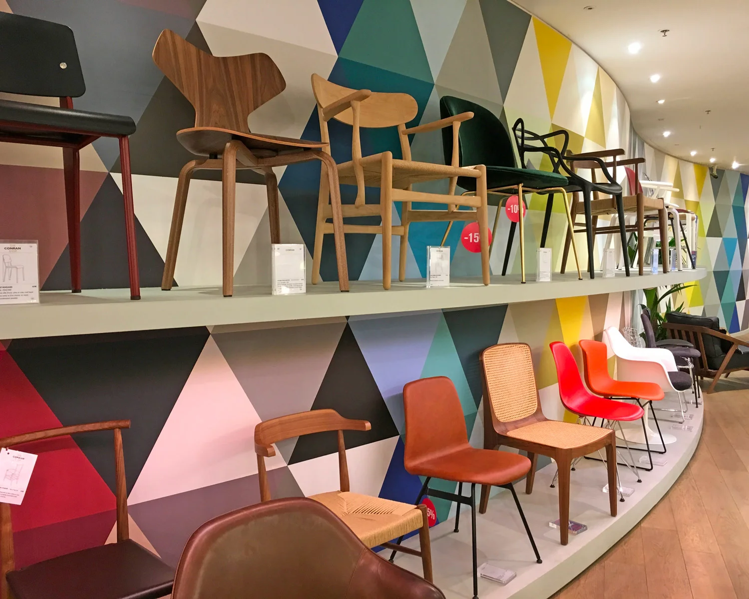 Various chairs at Conran Shop on display along an undulating, color-charged wall.