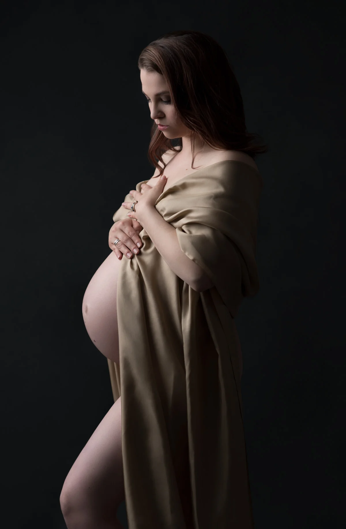 Dramatic maternity portrait with draped fabric.