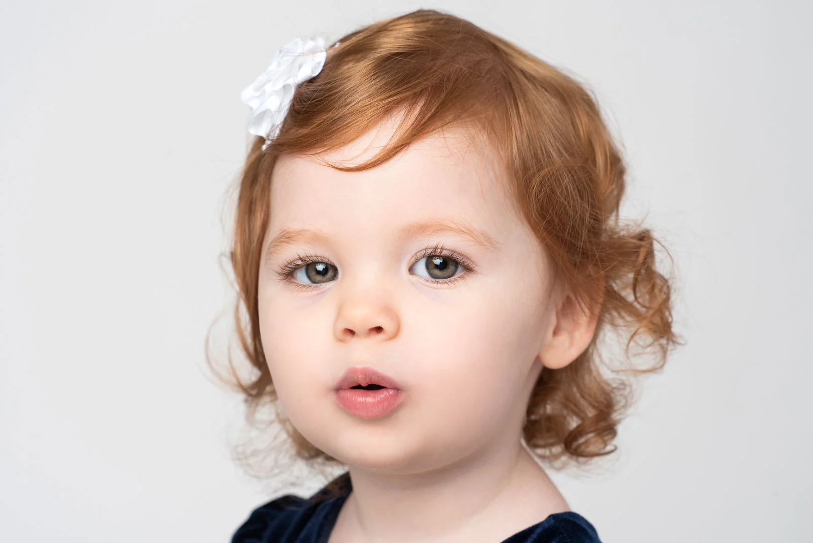 Christmas photo of redheaded toddler girl with white bow