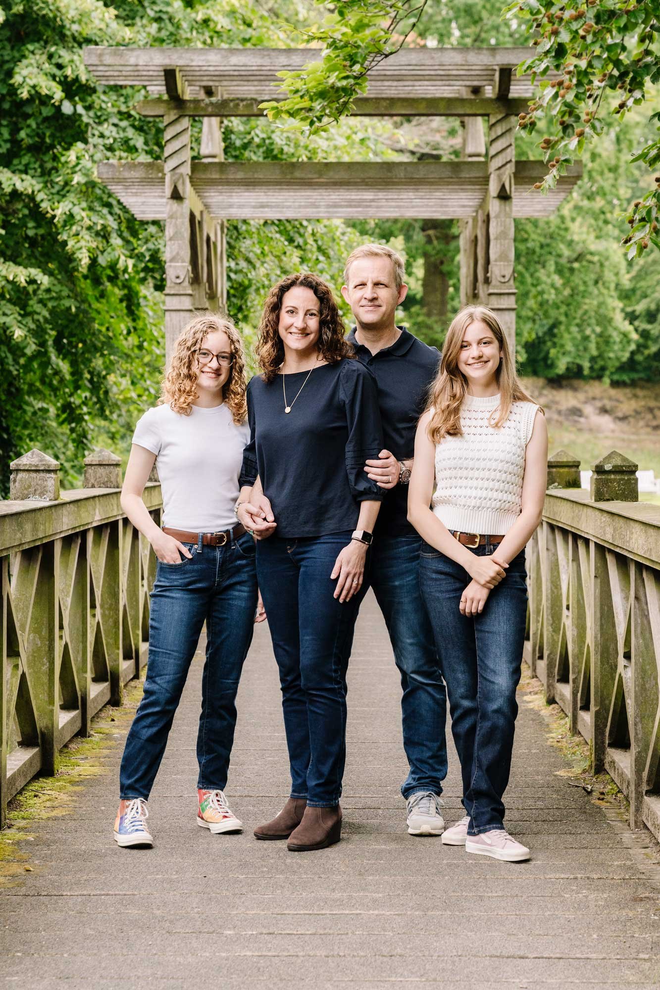 Photo of Parents and their two teenage daughters standing together on a bridge at a park in the Netherlands.