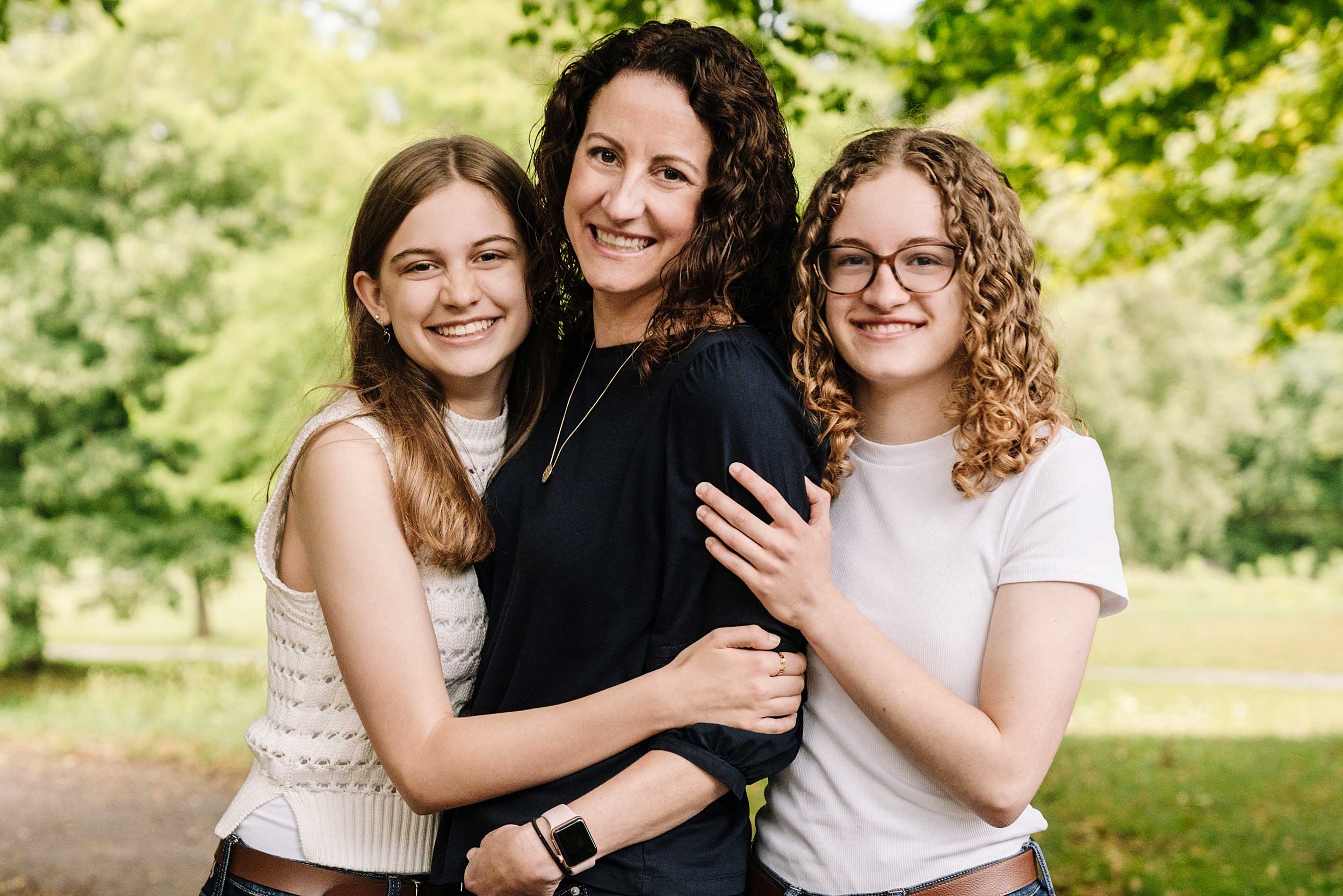 Portrait of a mother and her two daughters hugging and smiling in The Hague. 