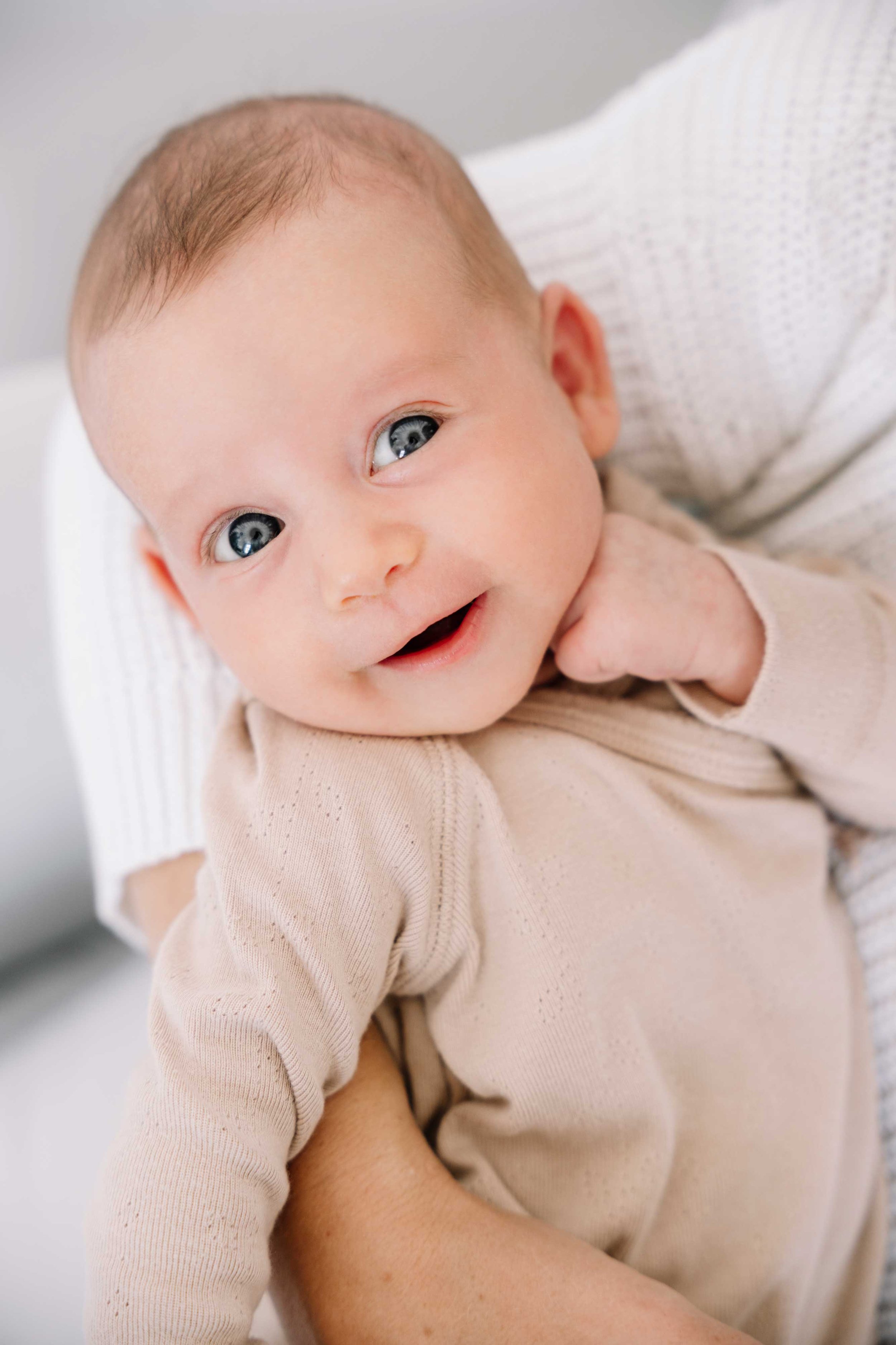 A lifestyle portrait of a newborn girl smiling.