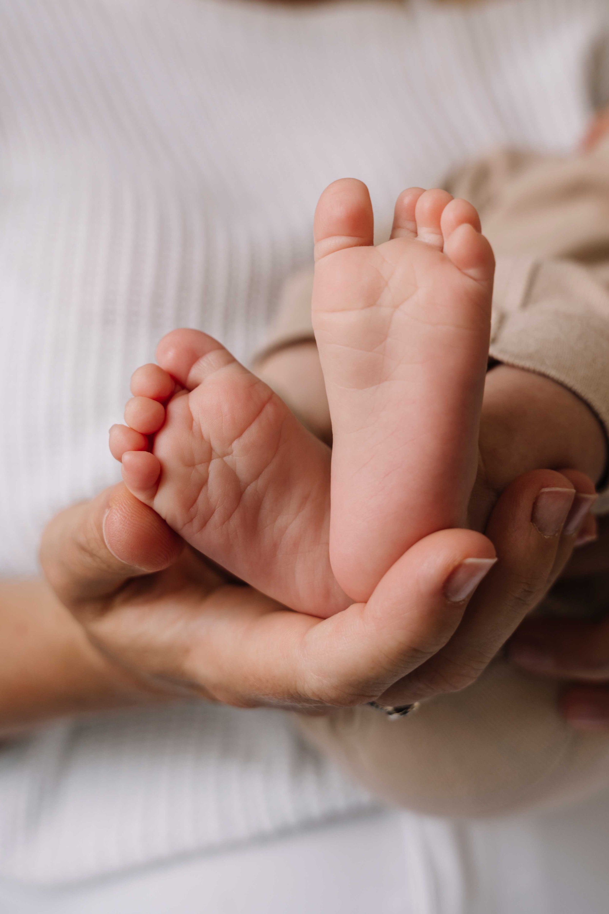 Mother holding her newborn baby's feet in her hands.