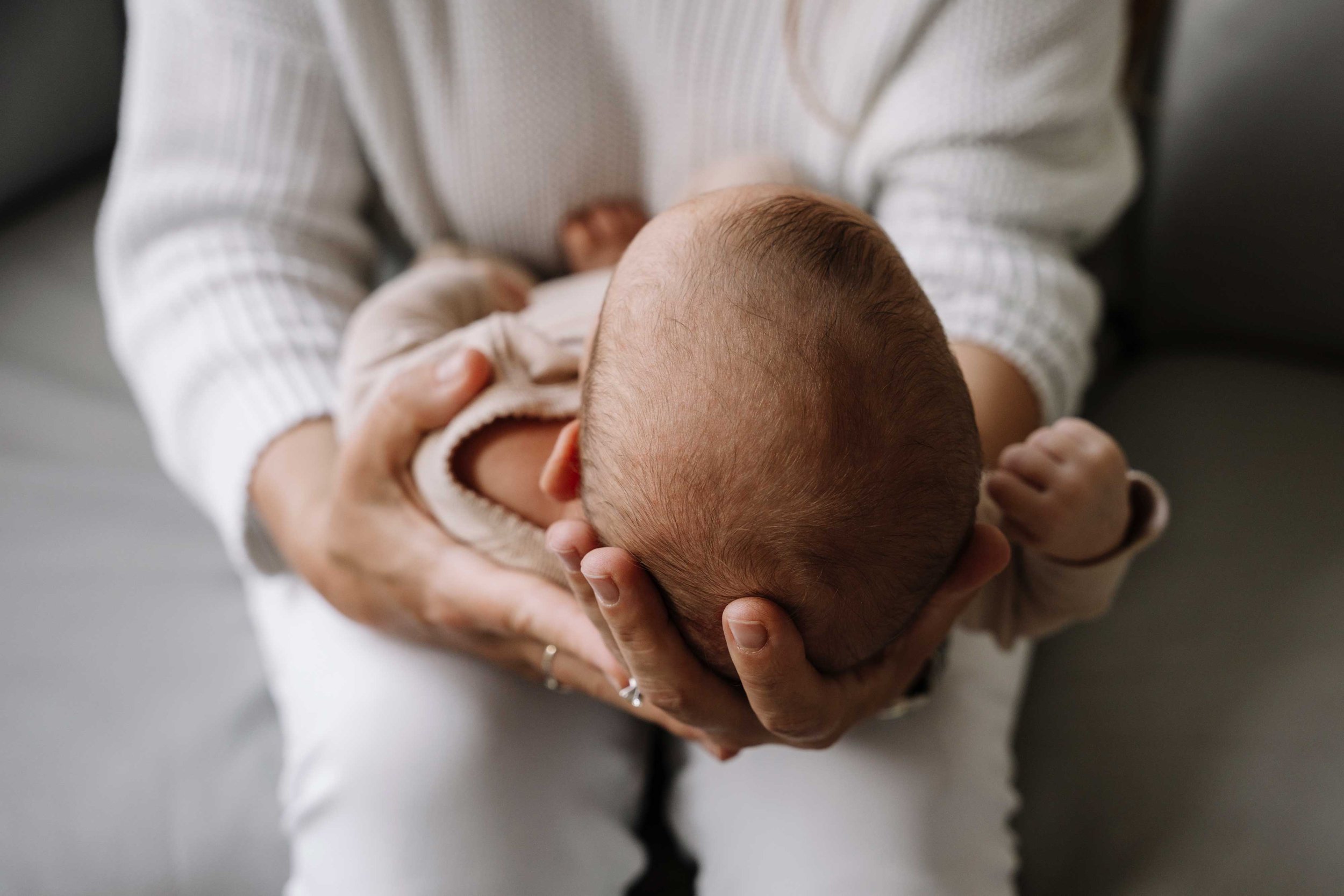 Baby's head cradled in her mother's hands.