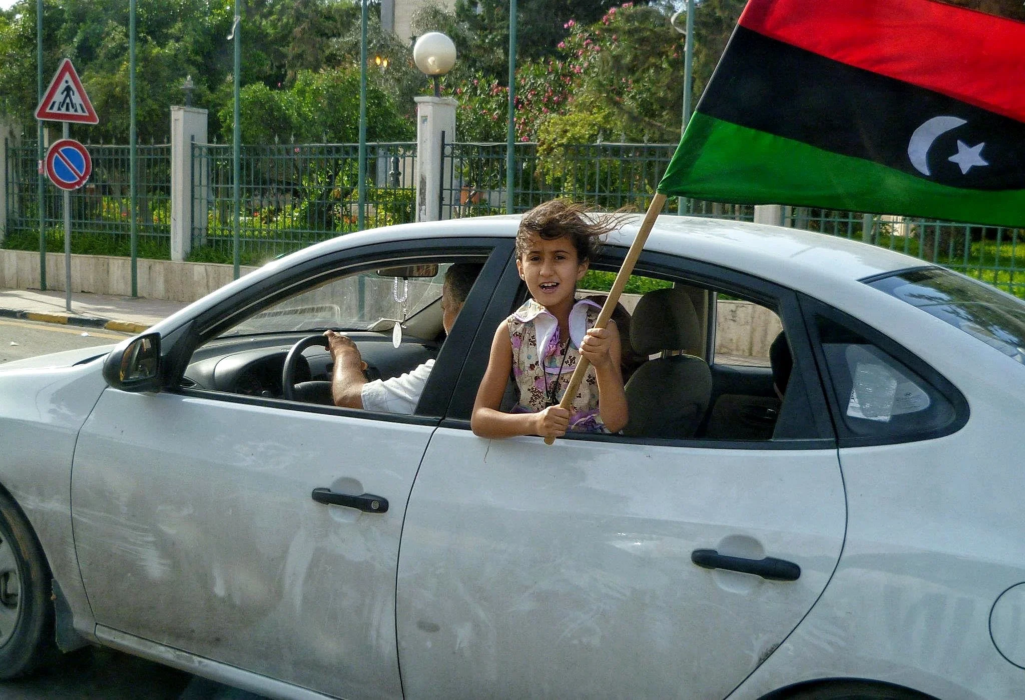 Child holding a Libyan flag through a car window — Tripoli, 20 October 2011
