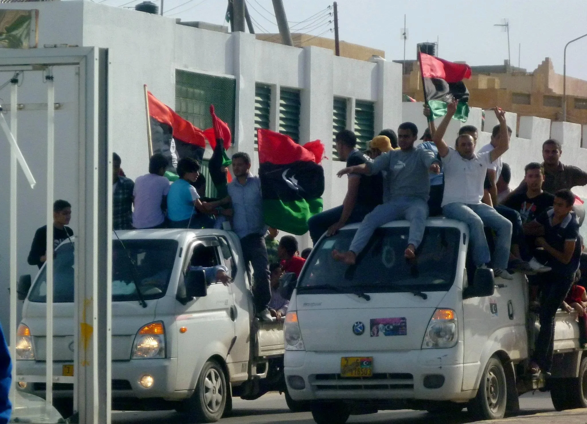 Crowds riding on minivans with Libyan flags — Tripoli, 20 October 2011
