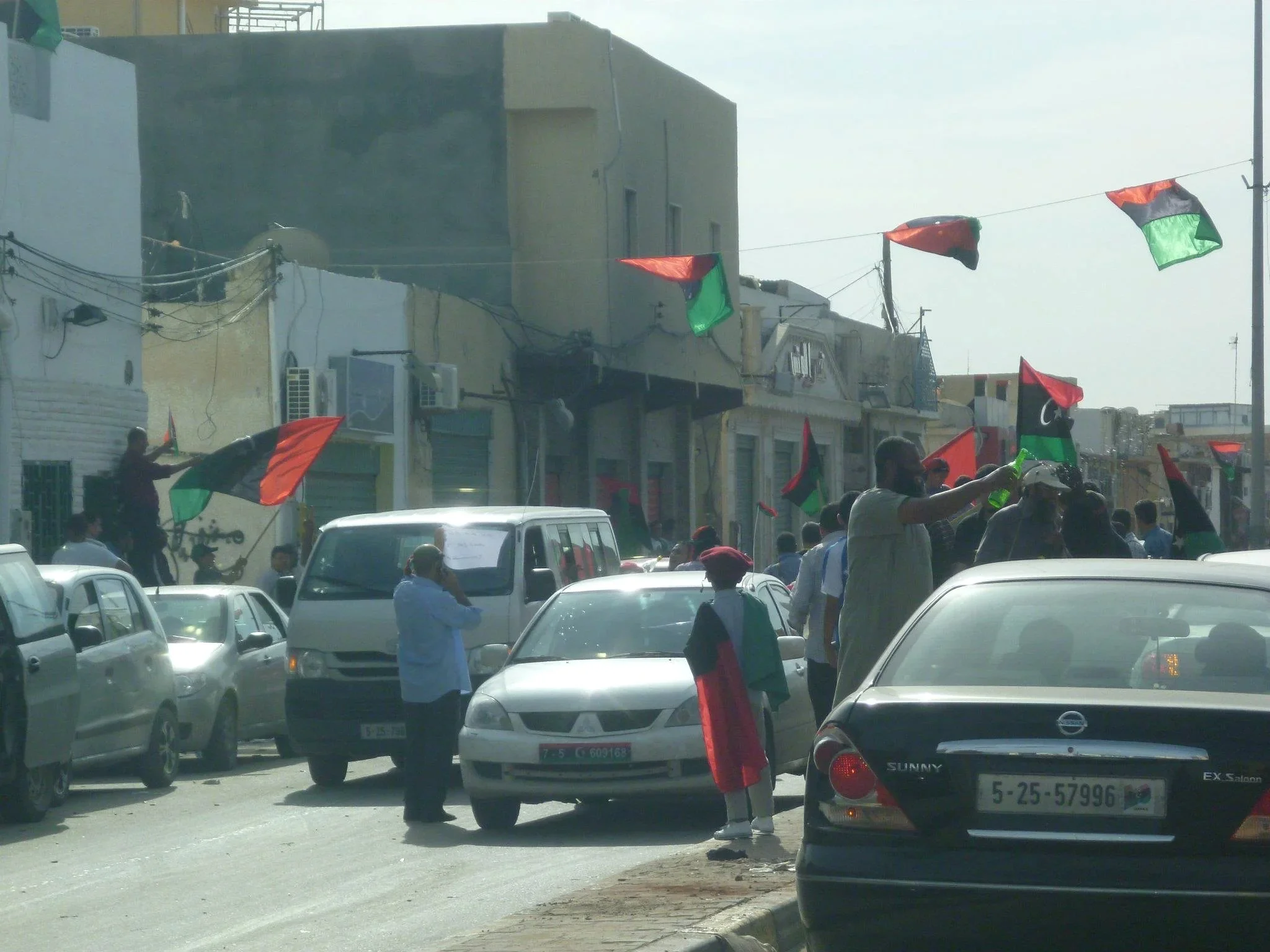 Flags and traffic on a neighbourhood street — Tripoli, 20 October 2011