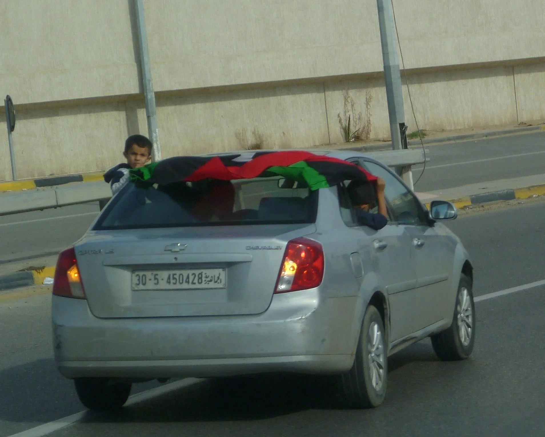 Children and flags in a silver sedan — Tripoli, 20 October 2011