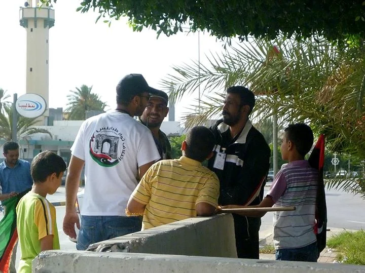 Men and children talking beneath palm trees — Tripoli, 20 October 2011