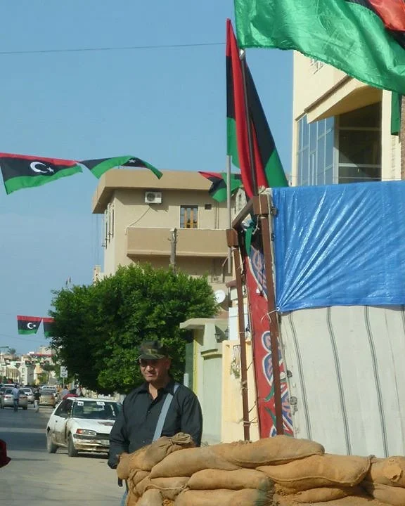 Libyan flags above sandbags at a street corner — Tripoli, 20 October 2011