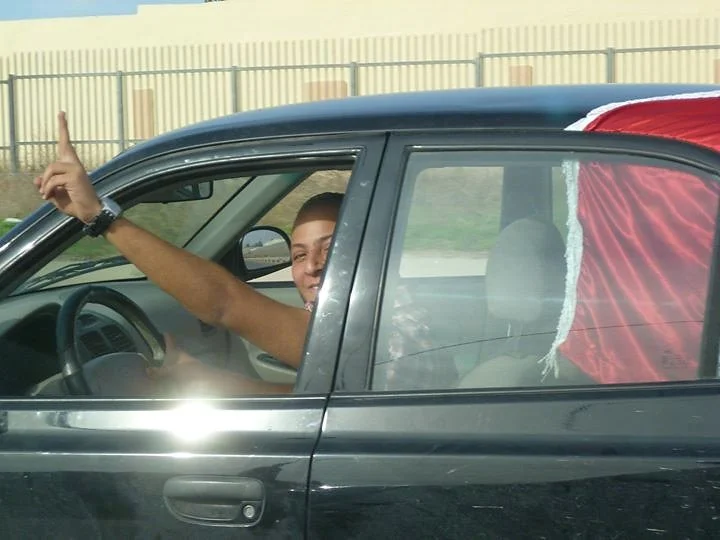 Driver making a victory sign beside a Libyan flag — Tripoli, 20 October 2011