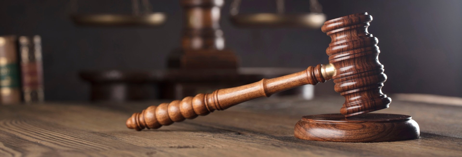 Umgestürzter Richterhammer aus Holz auf einer dunklen Oberfläche – Symbol für Recht und Gerechtigkeit.