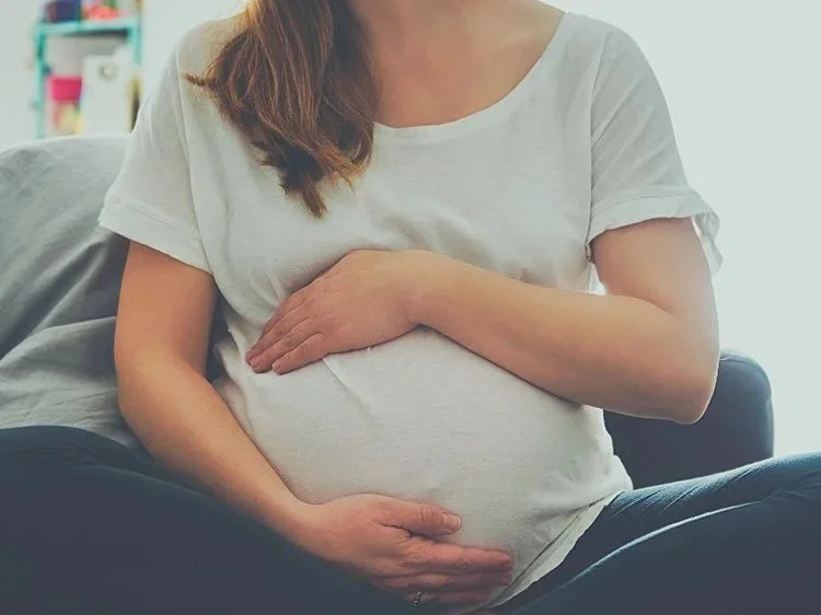pregnant woman holding belly during wellness checkin