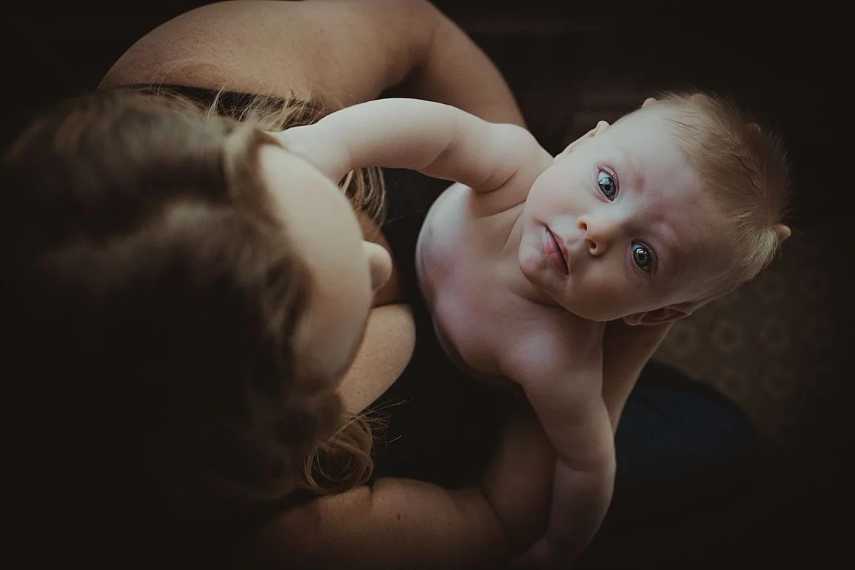nyc newborn and family photographer mom holding baby looking directly at camera