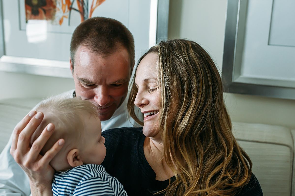 nyc newborn and family photographer mom and dad on couch and baby sleeping in arms