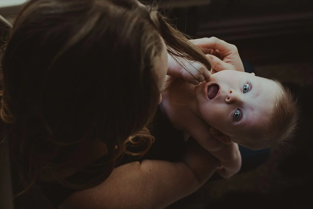 nyc newborn and family photographer mom and baby playing and baby chewing mom's hair