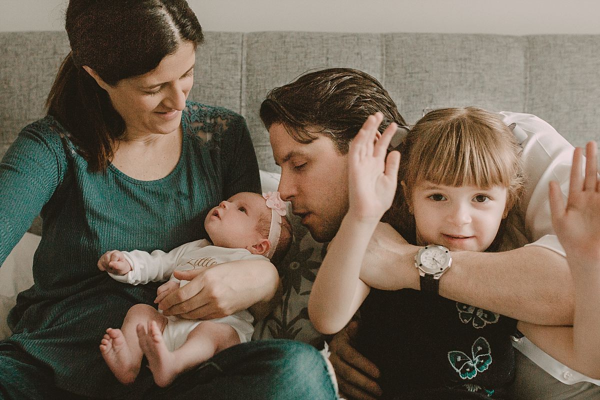 nyc family and newborn photographer mom, dad, big sister and newborn on couch