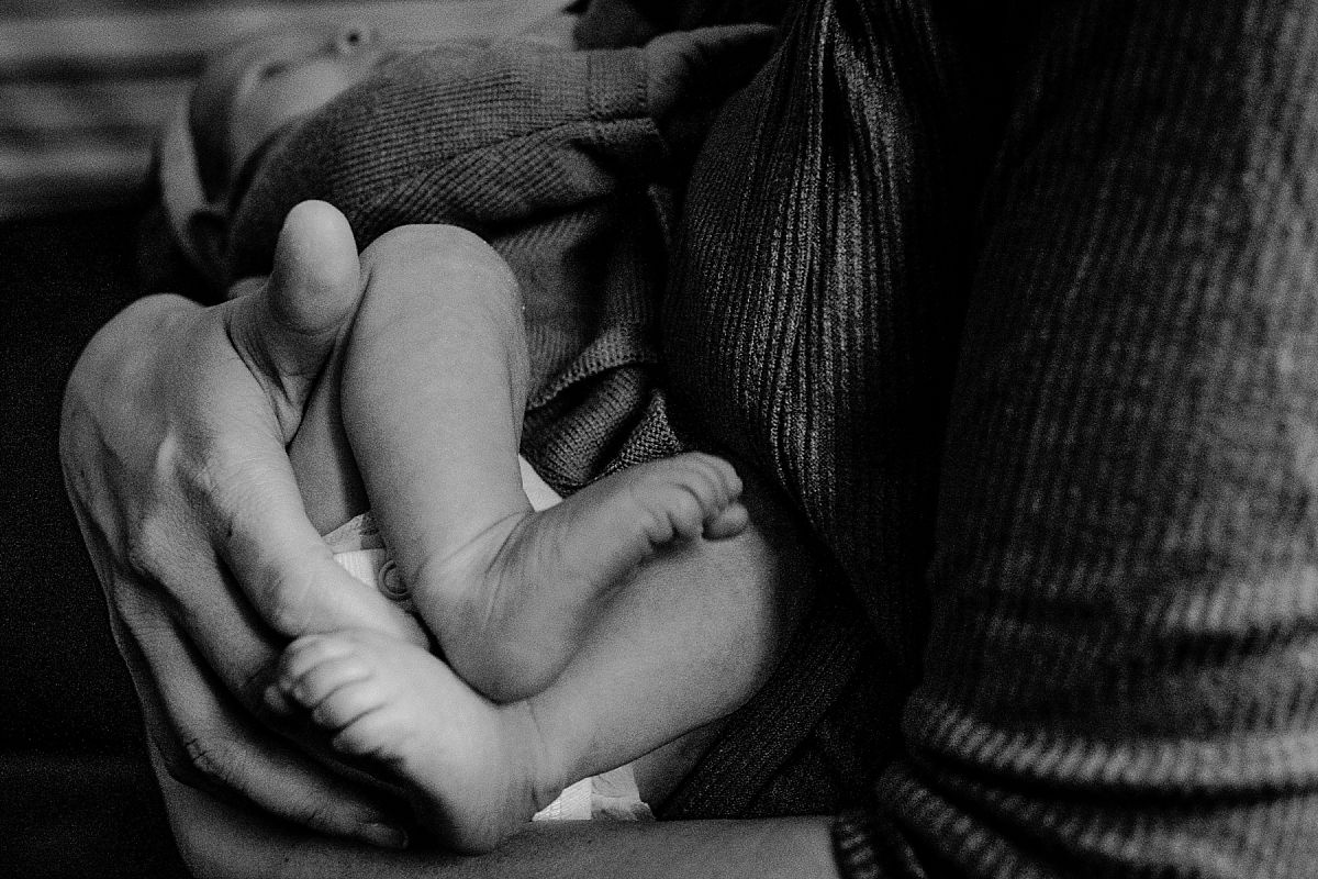 nyc family and newborn photographer mom holding newborn feet on couch