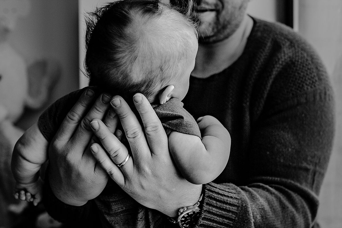 nyc family and newborn photographer dad holds newborn son closeup on window sill