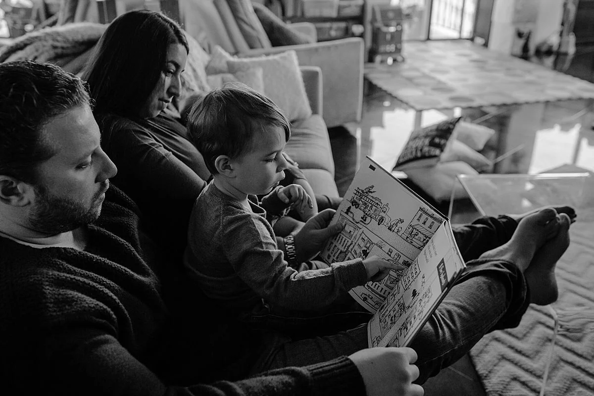 nyc family and newborn photographer family of four reads book together on couch