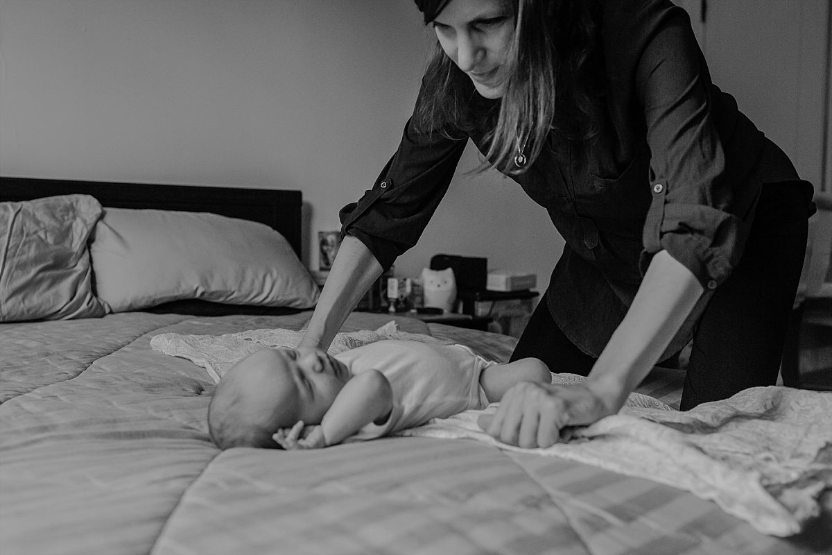 nyc family and newborn photographer Israeli mom lies newborn boy on bed and looks lovingly at him