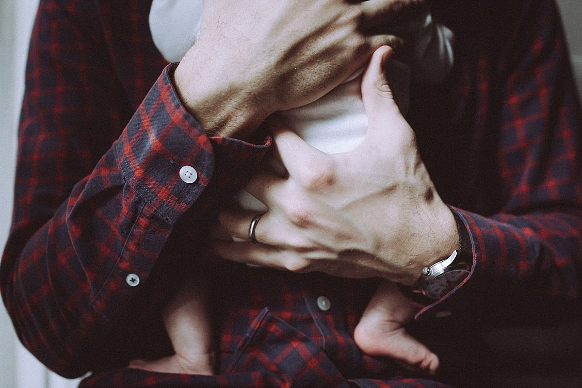 nyc family and newborn photographer new dad holds newborn baby girl in Chelsea abode and baby feet dangle