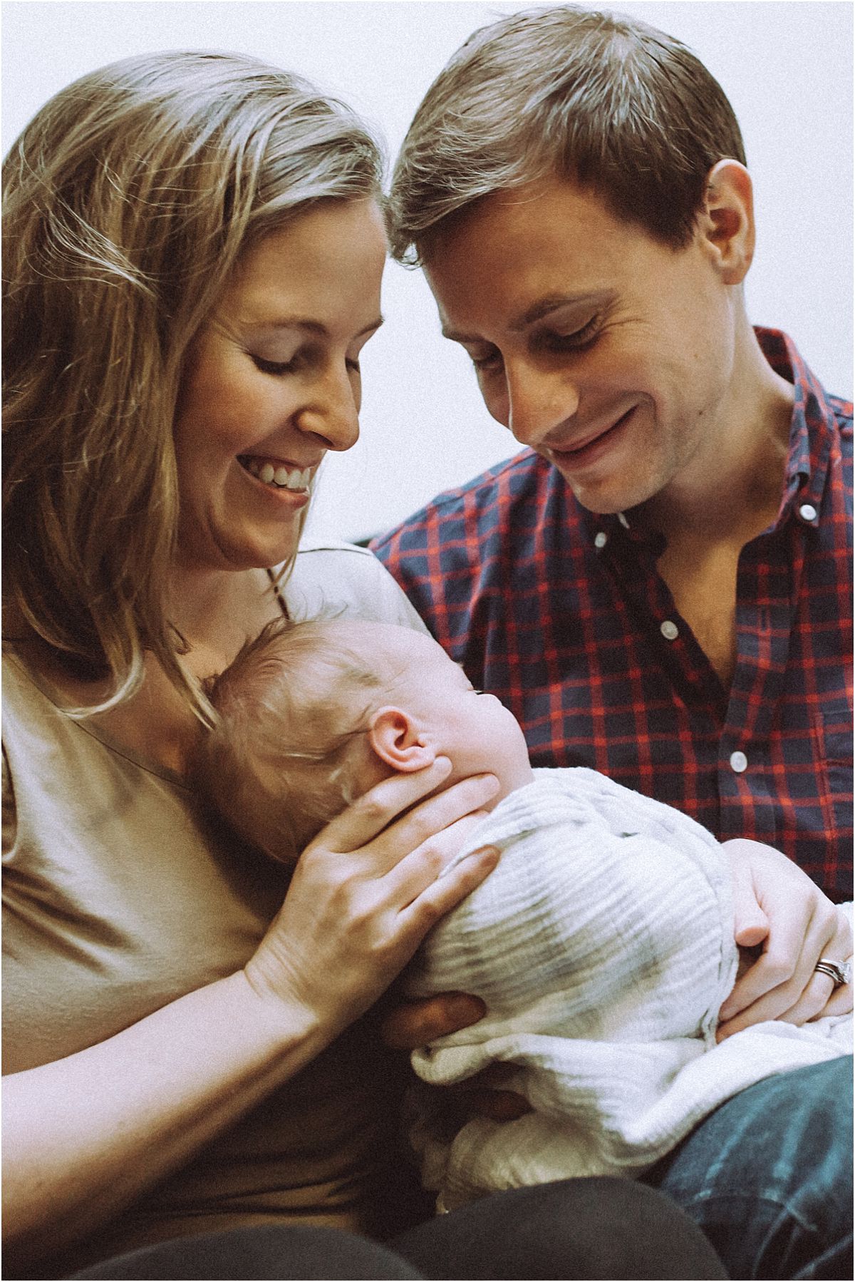 nyc family and newborn photographer mom, dad and newborn baby girl sit in stairwell while parents giggle with happiness