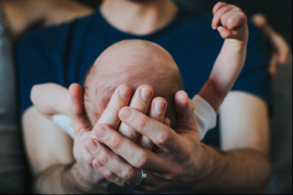 nyc family and newborn photographer dad holds newborn son in his hands while newborn outstretches his arm