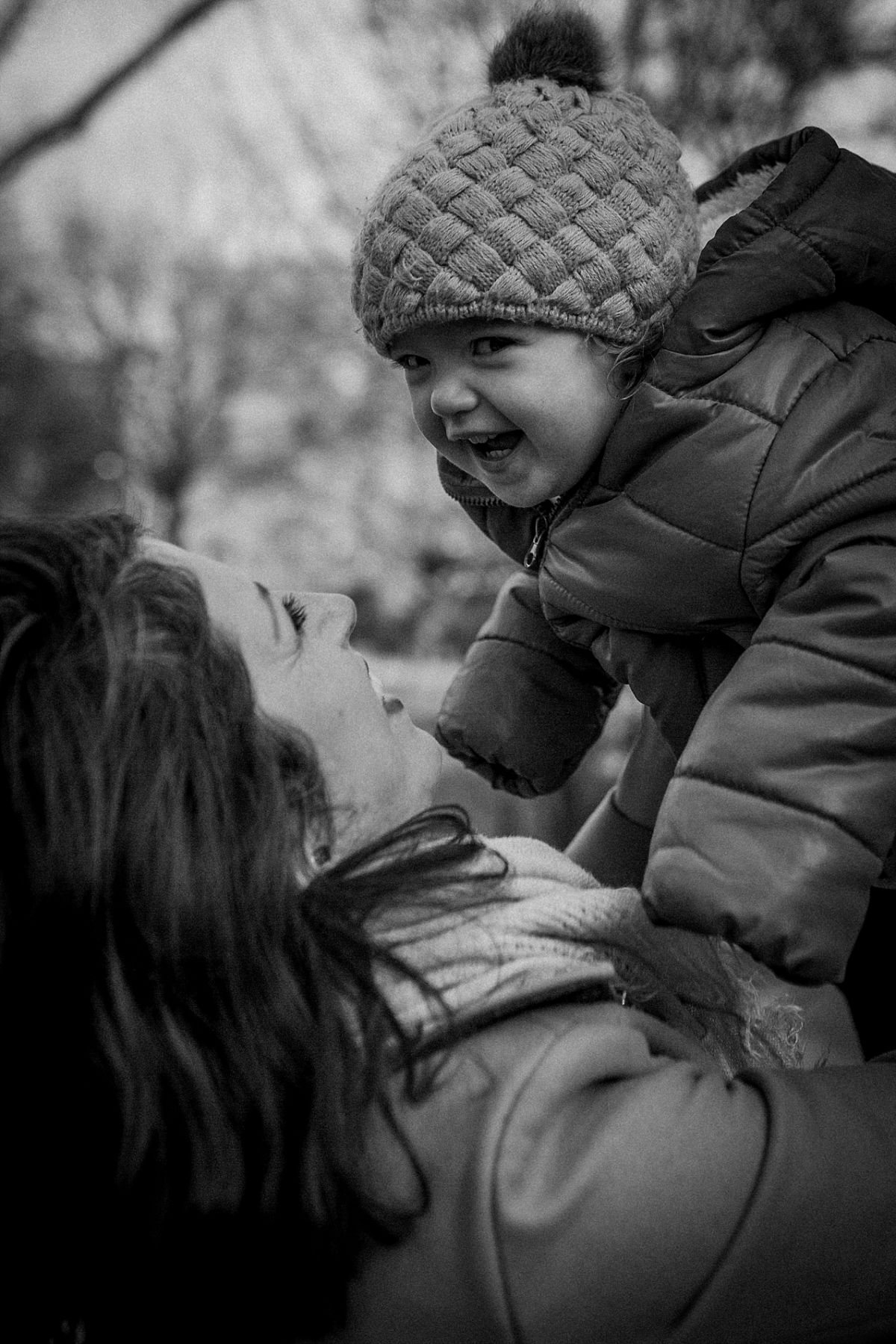 nyc family and newborn photographer mom holds toddler above head and they enjoy giggles together