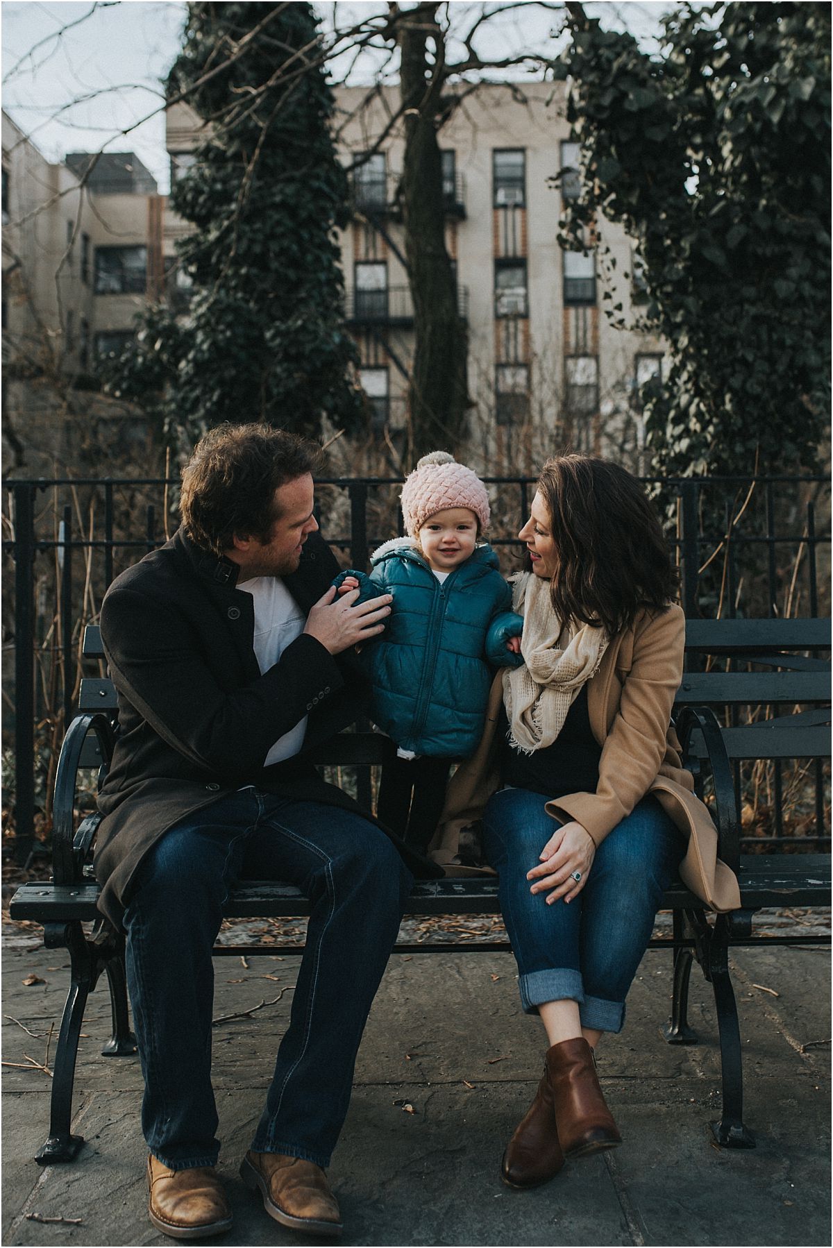 nyc family and newborn photographer family enjoying a moment sitting on nyc park bench on the upper west side