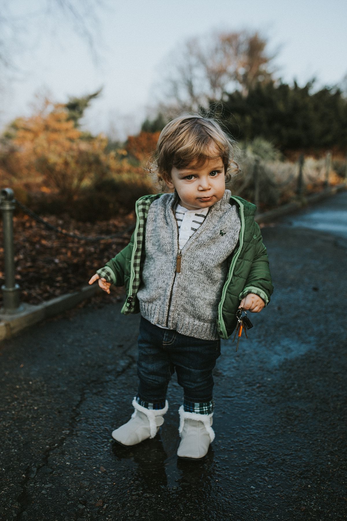 nyc family and newborn photographer toddler pulls silly face standing on path in nyc park