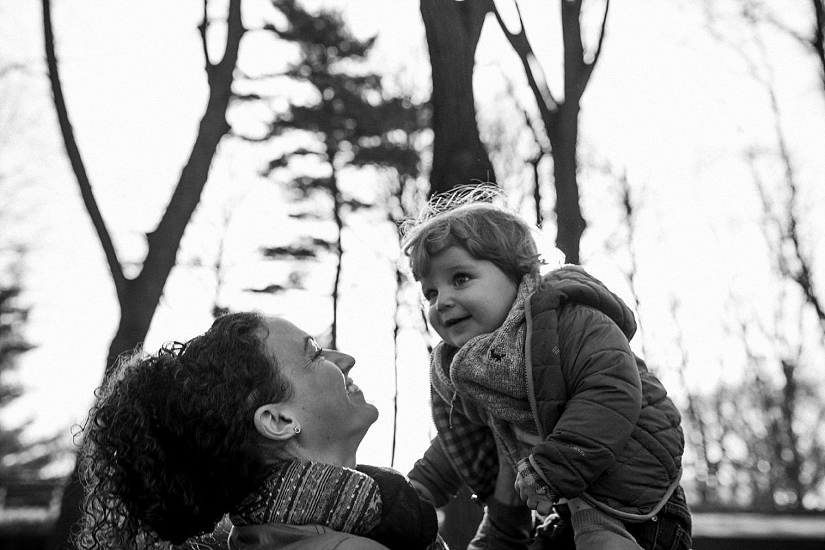 nyc family and newborn photographer mom throws toddler above up and down in nyc park
