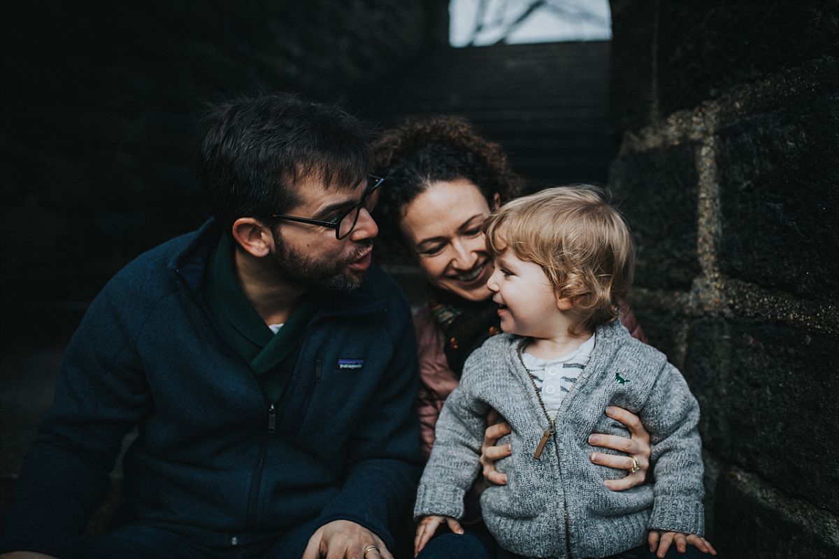 nyc family and newborn photographer dad pulls still faces to make toddler son laugh sitting on park steps