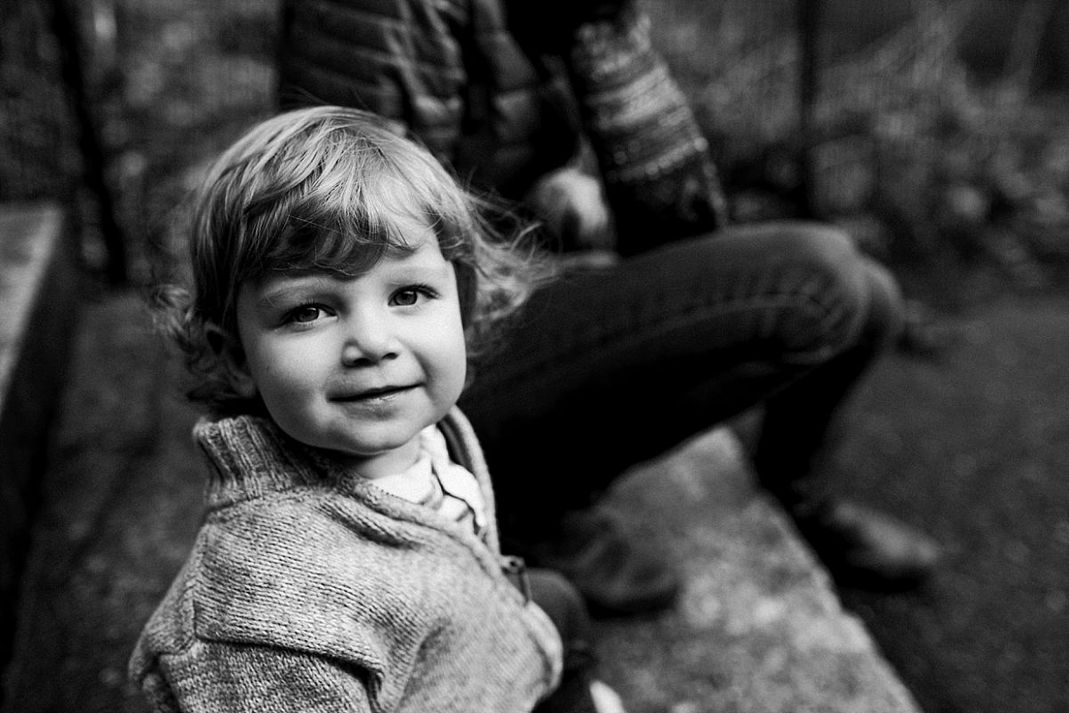 nyc family and newborn photographer portrait of toddler on steps with mom in background at nyc park